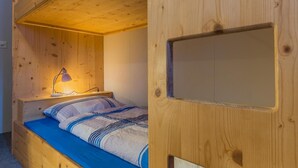 Cama litera con escritorio y lámpara, paredes de madera y una ventana.