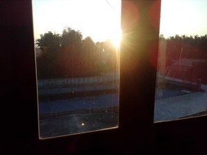 A window with a view of a parking lot and a building in the background.