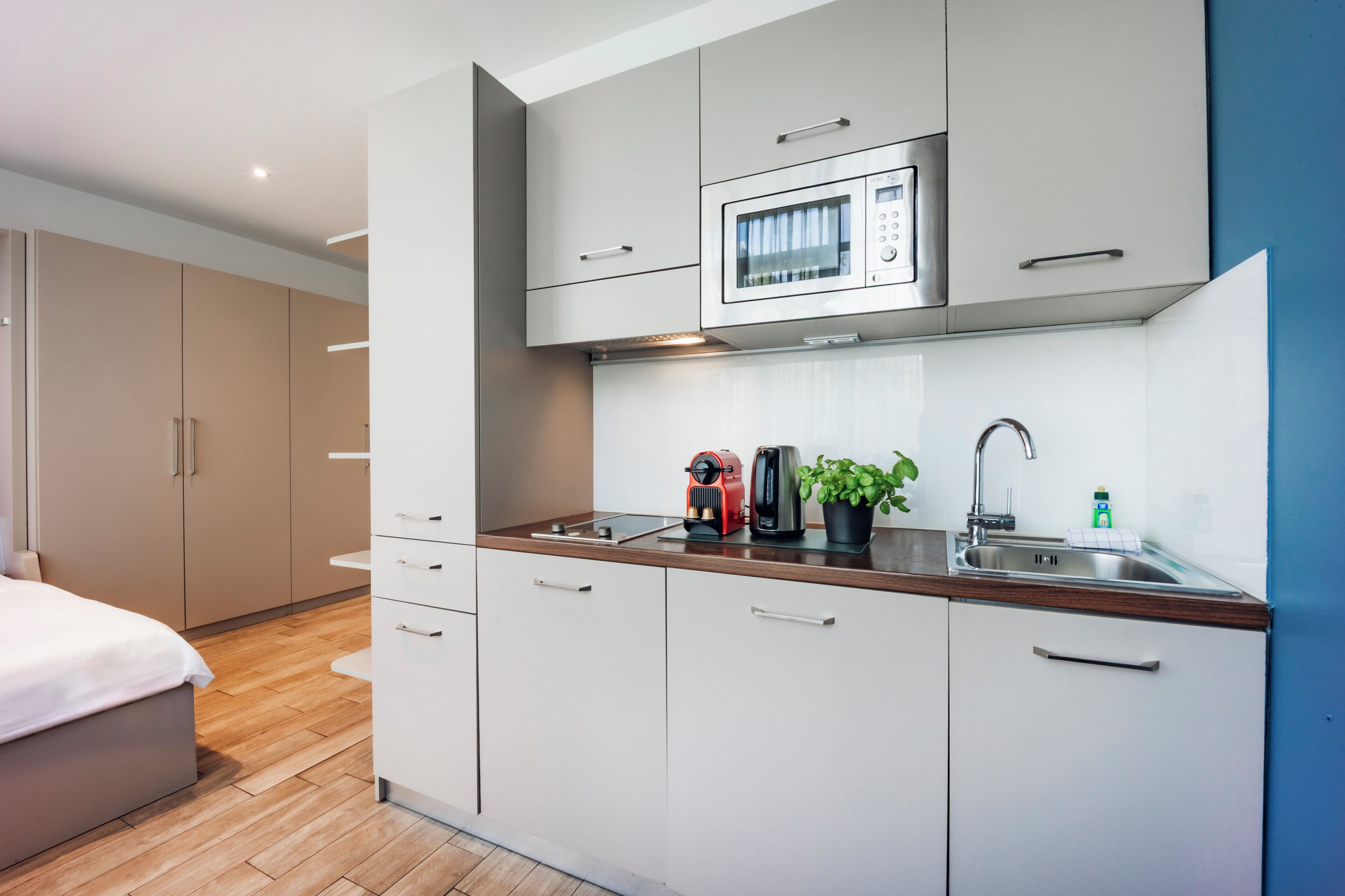 A modern kitchen with a microwave, coffee maker, and sink.