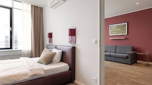 Una habitación de hotel moderna con una cama grande, un sofá gris y un cuadro en la pared.