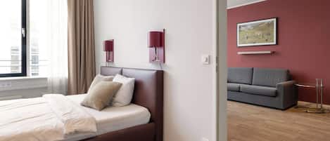Una habitación de hotel moderna con una cama grande, un sofá gris y un cuadro en la pared.