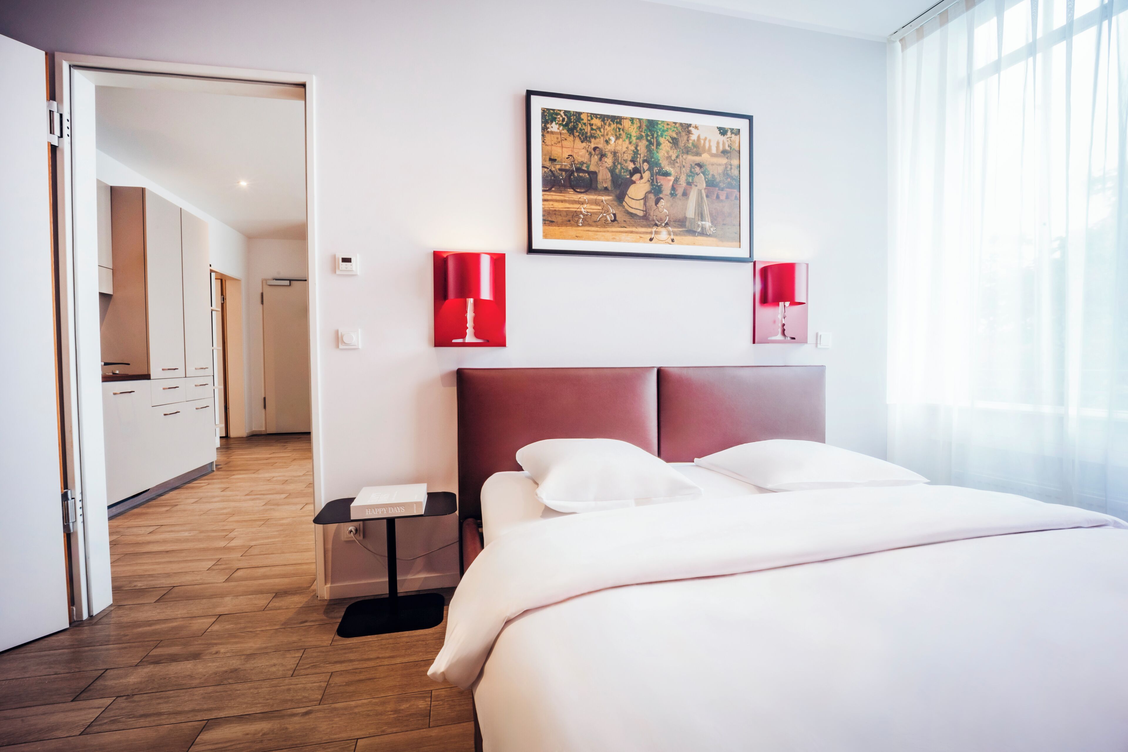 A hotel room with a large bed, a painting on the wall, and a view of the hallway.