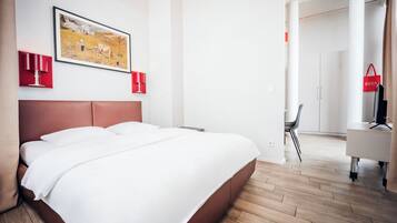 Ein Hotelzimmer mit einem großen Bett, einem Schreibtisch, einem Sessel und einem Fernseher.