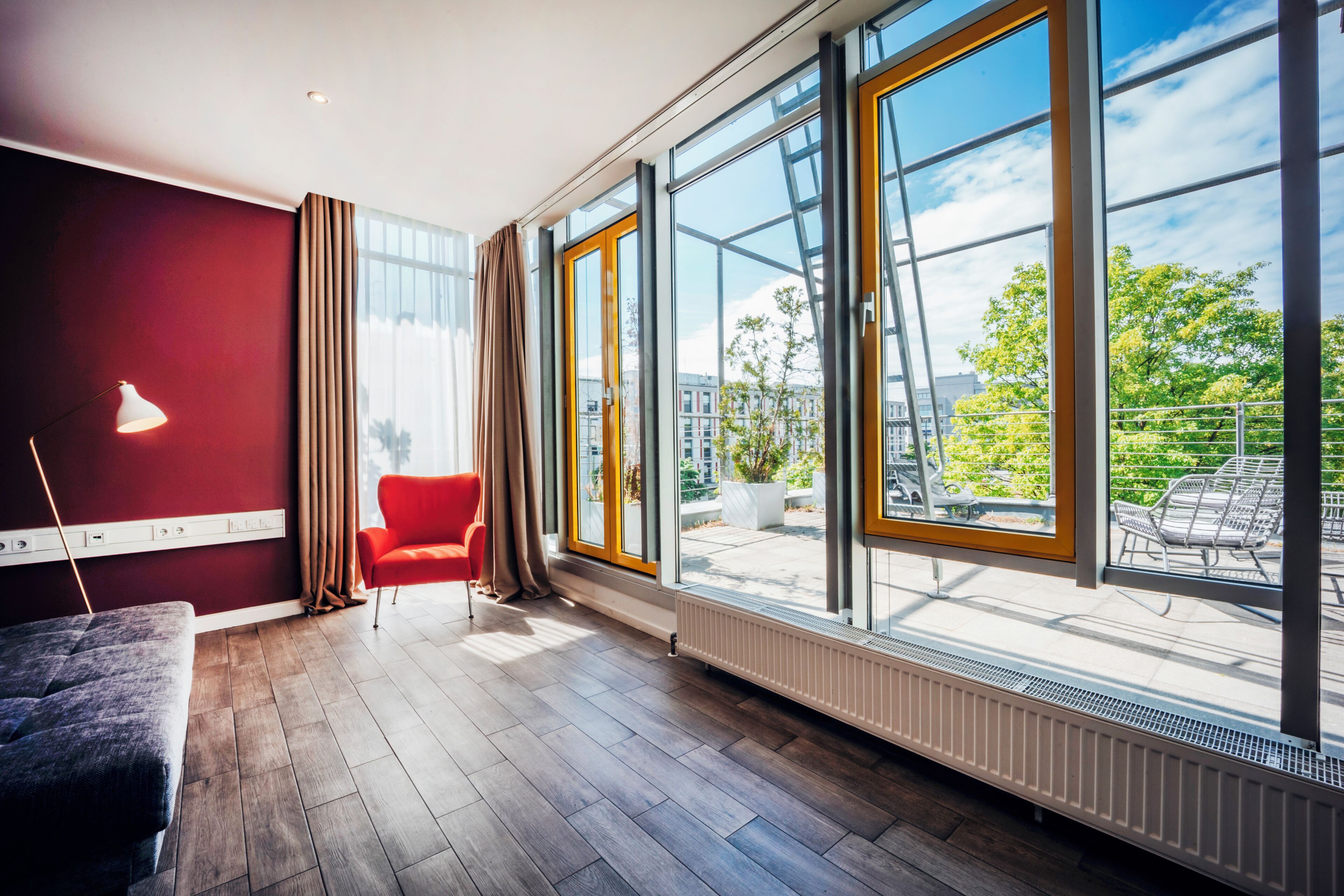 Una habitación moderna con un amplio ventanal, una silla roja y una lámpara.