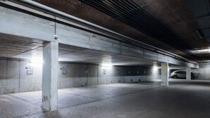 A multi-level underground parking garage with concrete pillars, marked parking spaces, and a tiled floor. - Brera Serviced Apartments Munich West (Munich)