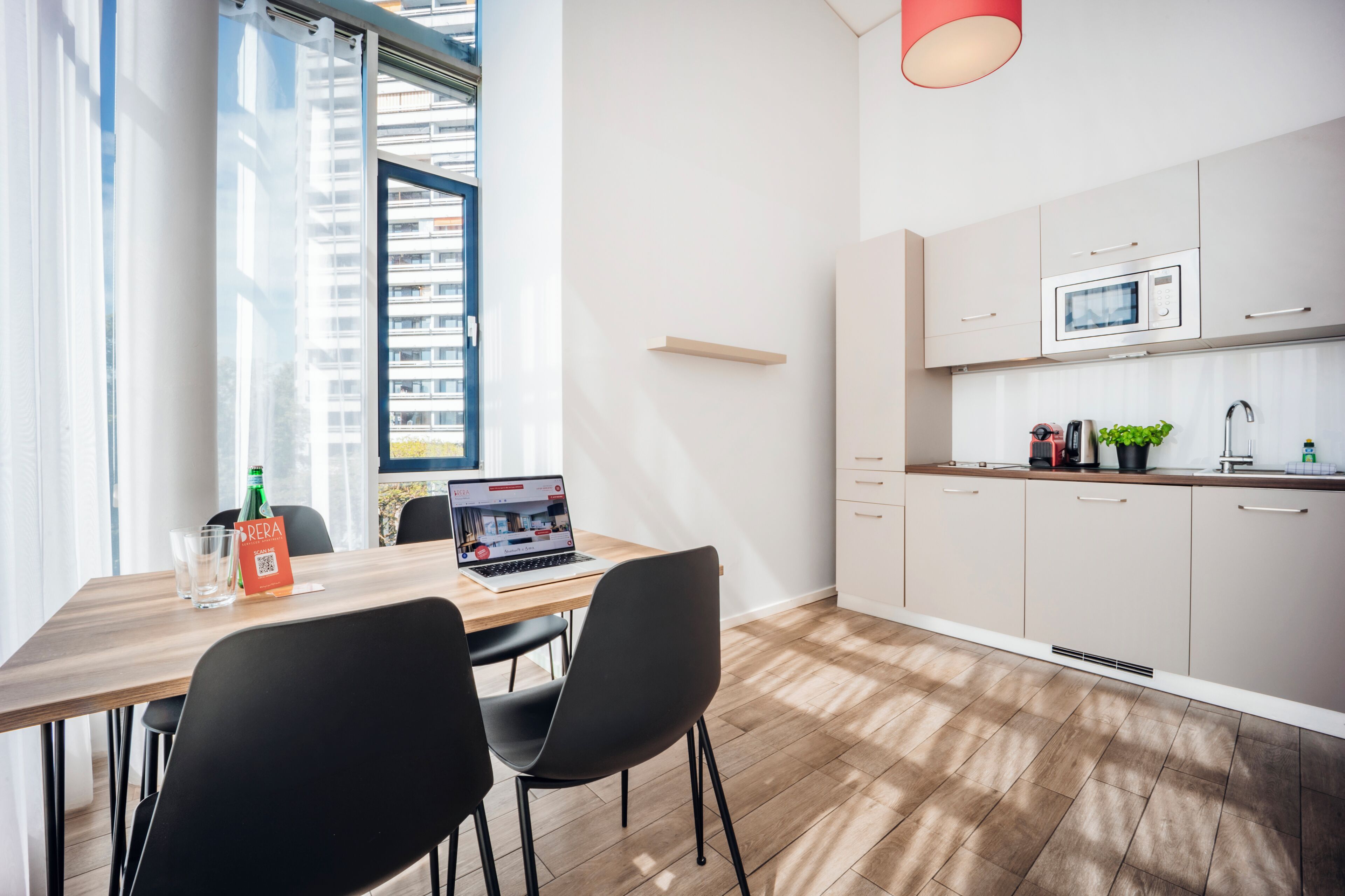 A modern kitchen with a microwave, a coffee machine, and a small plant on the counter.