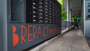 A building facade with a row of mailboxes and a sign that reads 'BRERA Check-In >'.