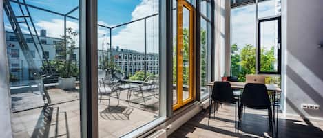 A modern interior with large windows, a dining area with chairs and a table, and a view of the cityscape.
