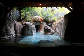 A stone pool with large rocks, surrounded by a wooden structure and a wooden fence. - Yamakawa ZENZO (Oguni)