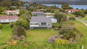 A residential area with houses, a grassy yard, and a body of water in the background. - Sunrise at Parapara Beach (Parapara)