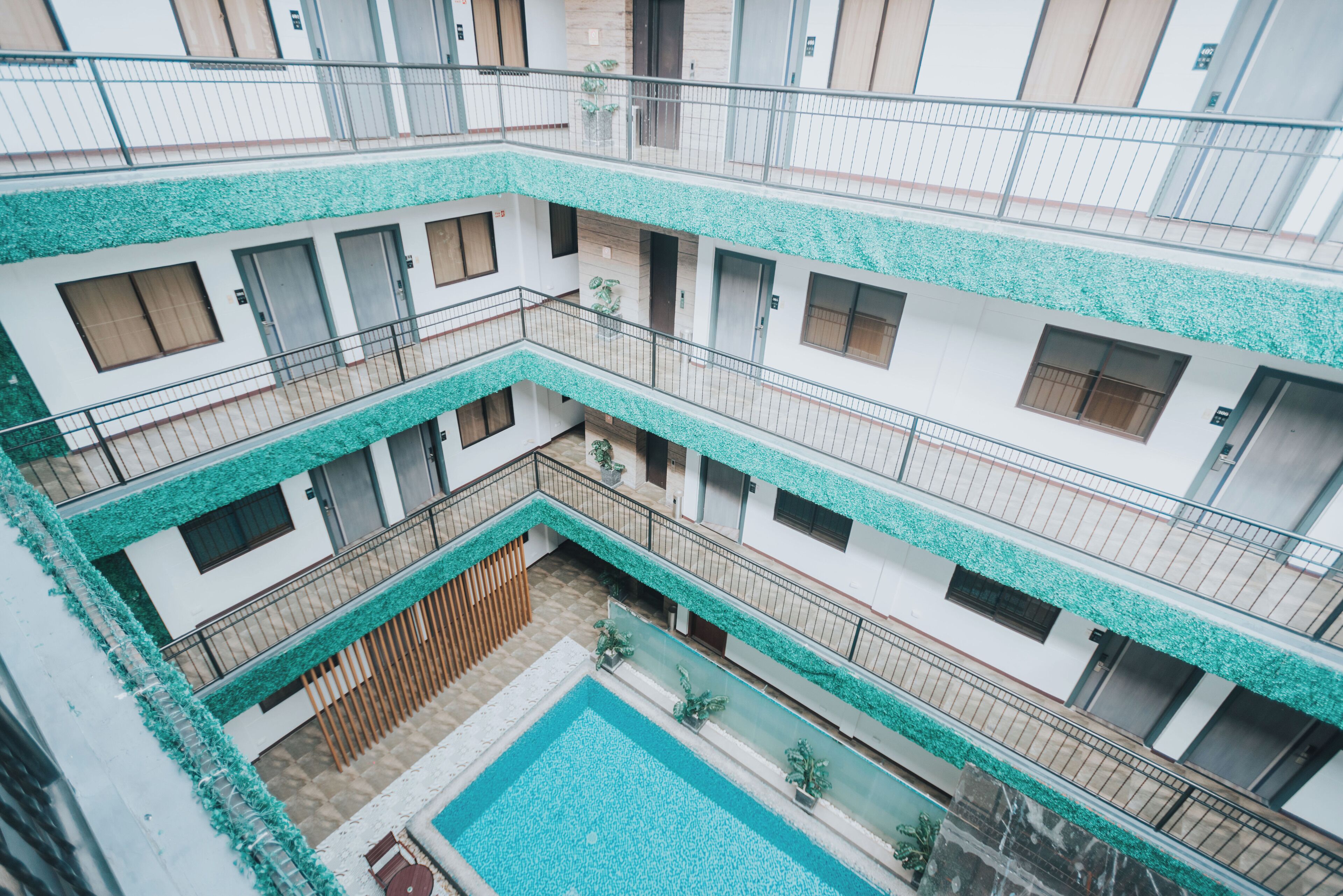 A multi-level hotel with balconies, a central courtyard with a pool, and a modern architectural design.