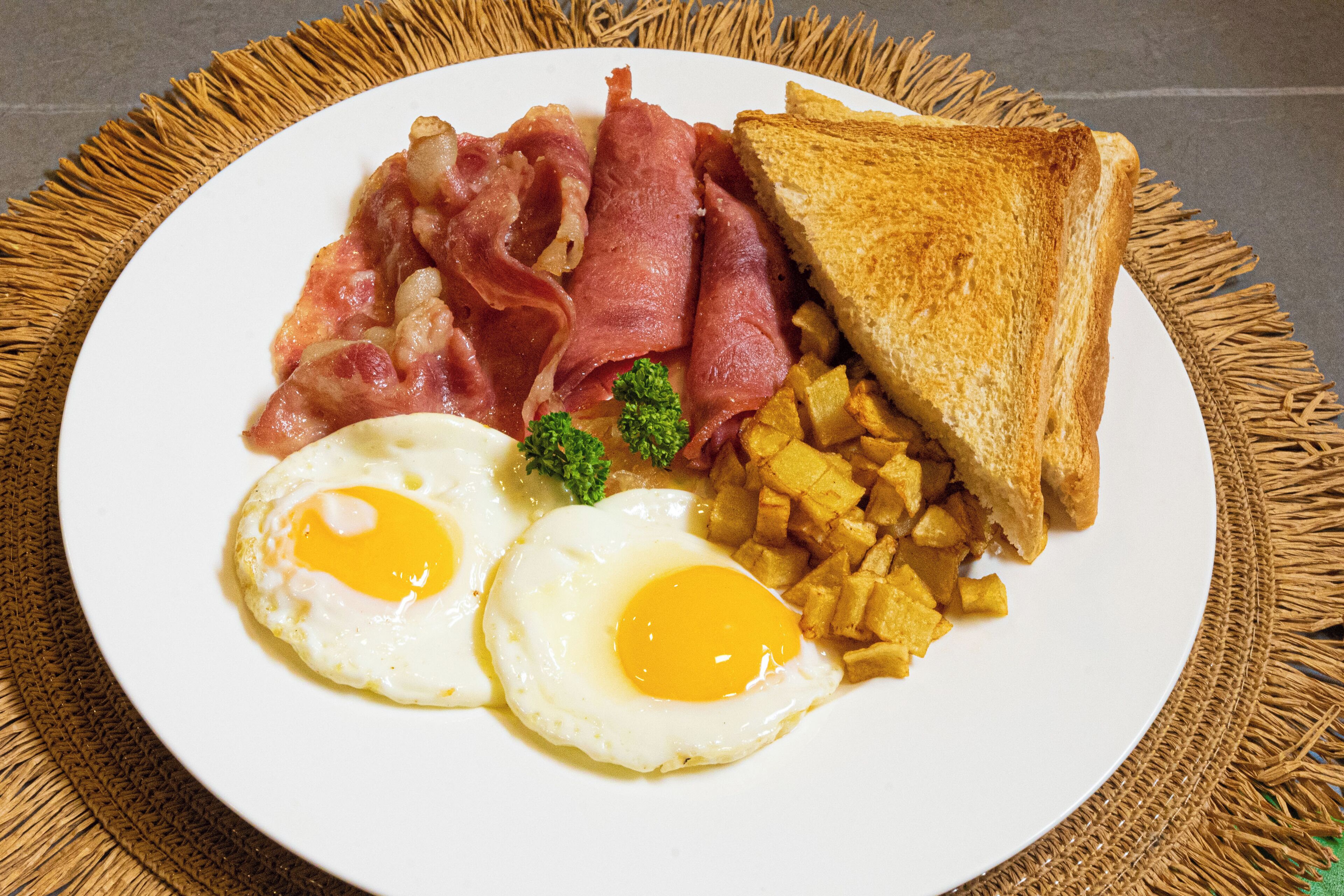 Un plato con huevos, tocino, tostadas y papas.