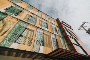 Ein modernes Gebäude mit einer markanten Fassade, die geometrische Muster und vertikale Lamellen aufweist.