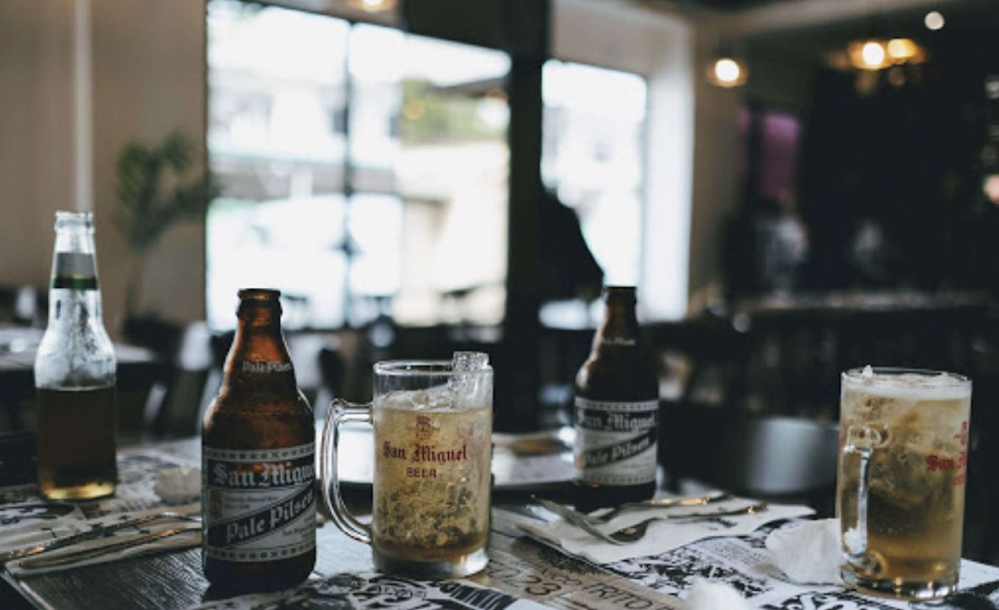 A bar setting with bottles and glasses of beer.