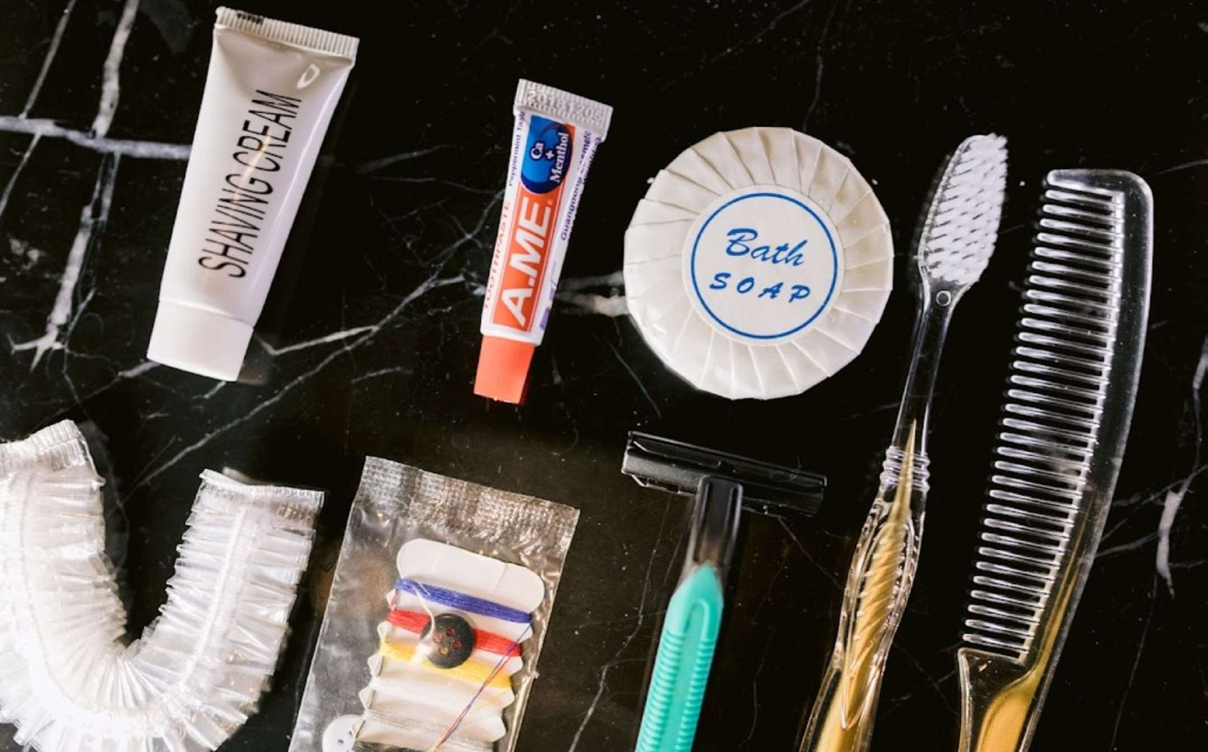 Divers produits d’hygiène personnelle, notamment de la crème à raser, un bain de bouche et du savon, sont disposés sur une surface en marbre.