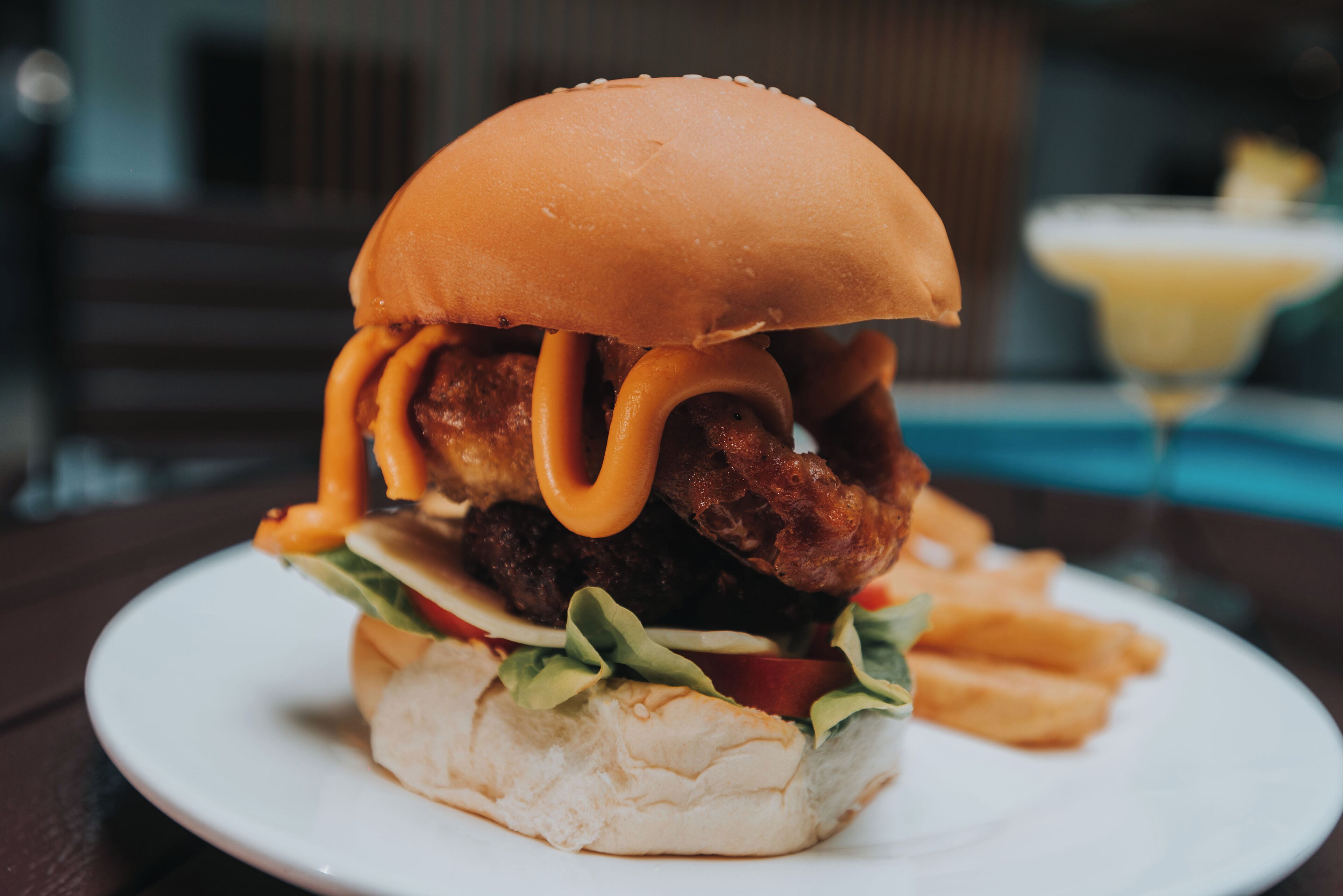 A sandwich with a bun, lettuce, tomato, and a fried item, served on a white plate.