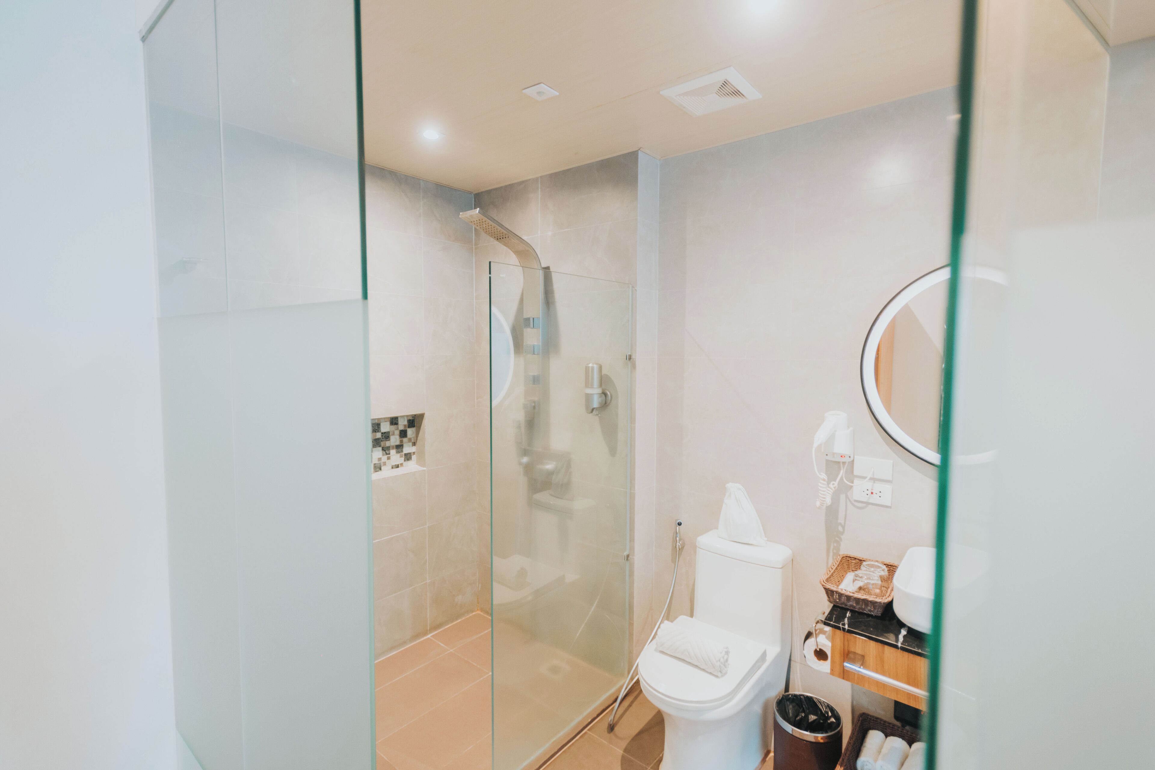 A modern bathroom with a glass-enclosed shower, a toilet, and a vanity with a mirror.