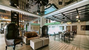 Um espaço interior amplo, com teto alto, soalho de madeira e uma variedade de opções de assento, incluindo uma poltrona de couro, um sofá e uma mesa de jantar com cadeiras.
