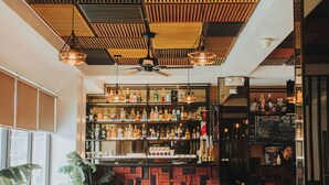 Um bar moderno com piso de madeira, diversos tipos de assentos e um bar bem abastecido.