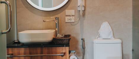 Ein Badezimmer mit rundem Spiegel, Waschbecken, Toilette und Mülleimer.