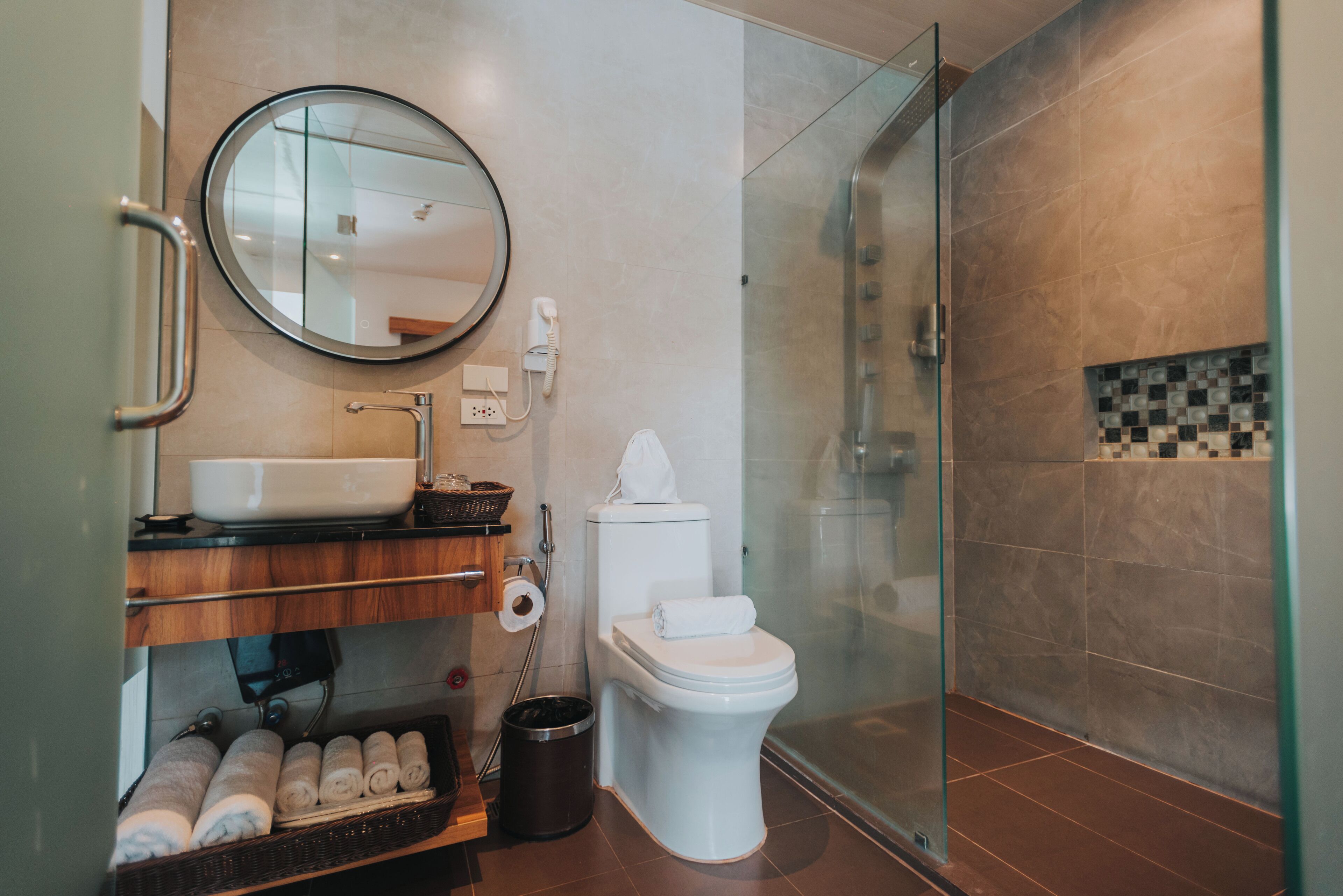 A modern bathroom with a glass-enclosed shower, a white toilet, and a sink with a mirror above it.