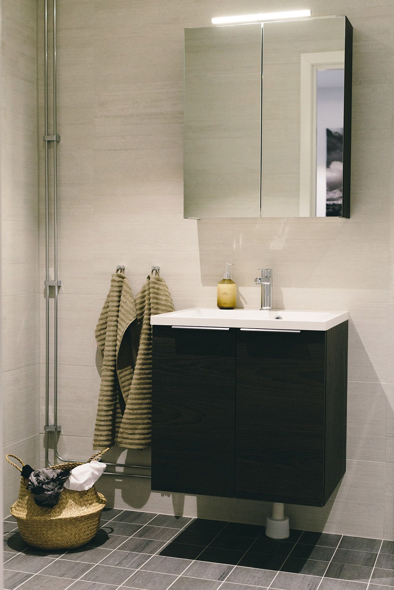 A modern bathroom with a dark vanity, a large mirror, and a shower area.