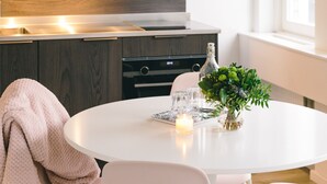 Una cocina moderna con armarios de madera, una mesa de comedor blanca con sillas, y un jarrón con plantas.