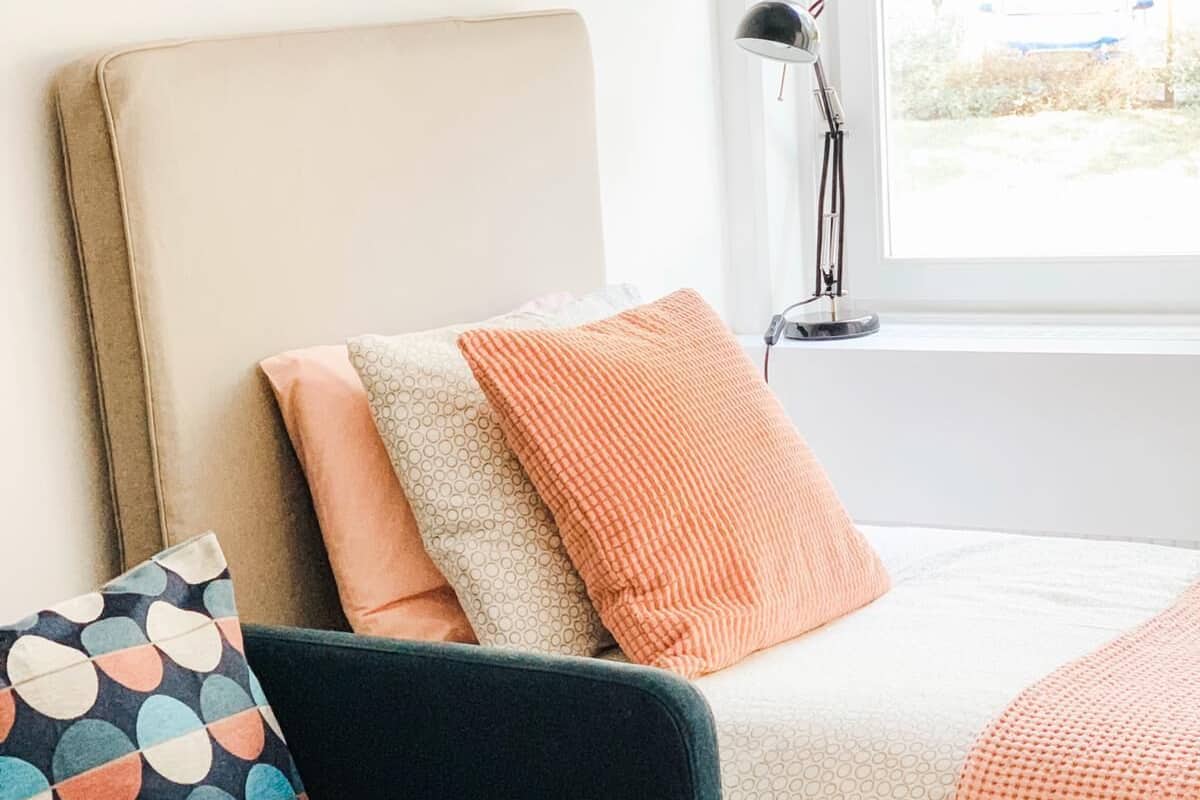 Un dormitorio con cama, una silla y una ventana.