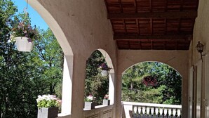 Un espace extérieur abrité, doté d’arcades, de jardinières suspendues et offrant une vue sur la verdure.