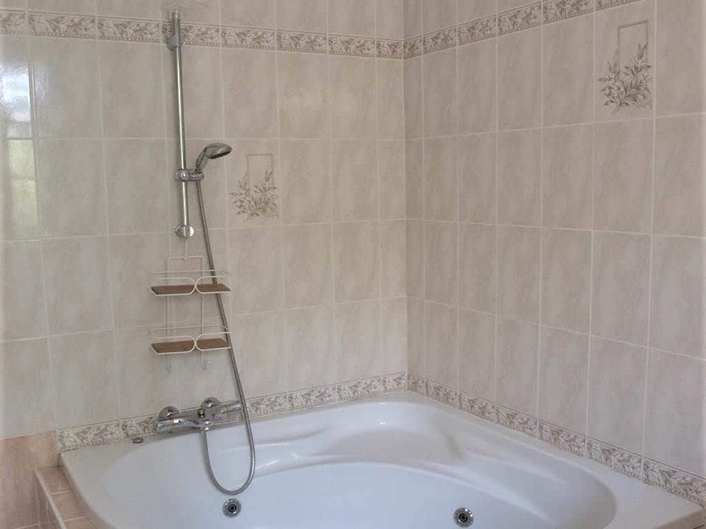 Een badkamer met een vrijstaand bad, een handdouche en een wandmengkraan.