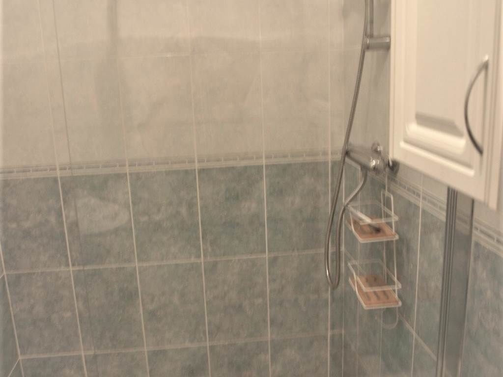 A tiled shower area with a glass door and a metal showerhead.