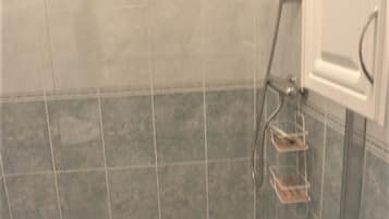 A tiled shower area with a glass door and a metal showerhead.