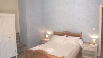 A bedroom with a wooden bed, two bedside tables with lamps, a wardrobe, and a chair.