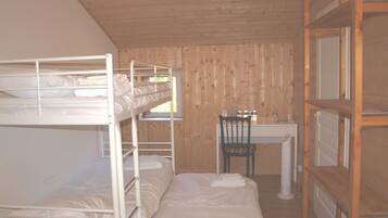 Een slaapkamer met stapelbed, bureau en stoel, houten wanden en een raam.