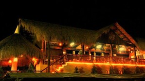 Ein großes Gebäude mit einem Strohdach und mehreren Balkonen, vermutlich ein Resort oder Hotel.