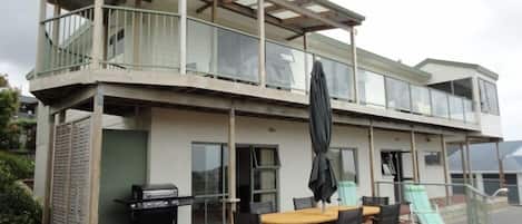 A two-story building with a balcony, a barbecue grill, and outdoor seating.