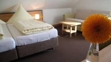 A hotel room with a bed, a small table, and a vase with a flower.