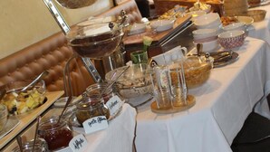 A buffet table with various food items and condiments, including jars of jam and a bowl of cereal. - Hotel Häußler (Reichertshofen)