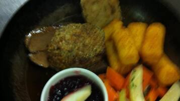 A plate with a variety of food items including a meat patty, fried items, and vegetables.