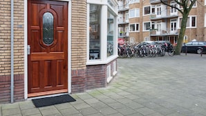 A brick building with a wooden door and a window. There are bicycles parked outside. - Bos en Lommer Apartments (Amsterdam)