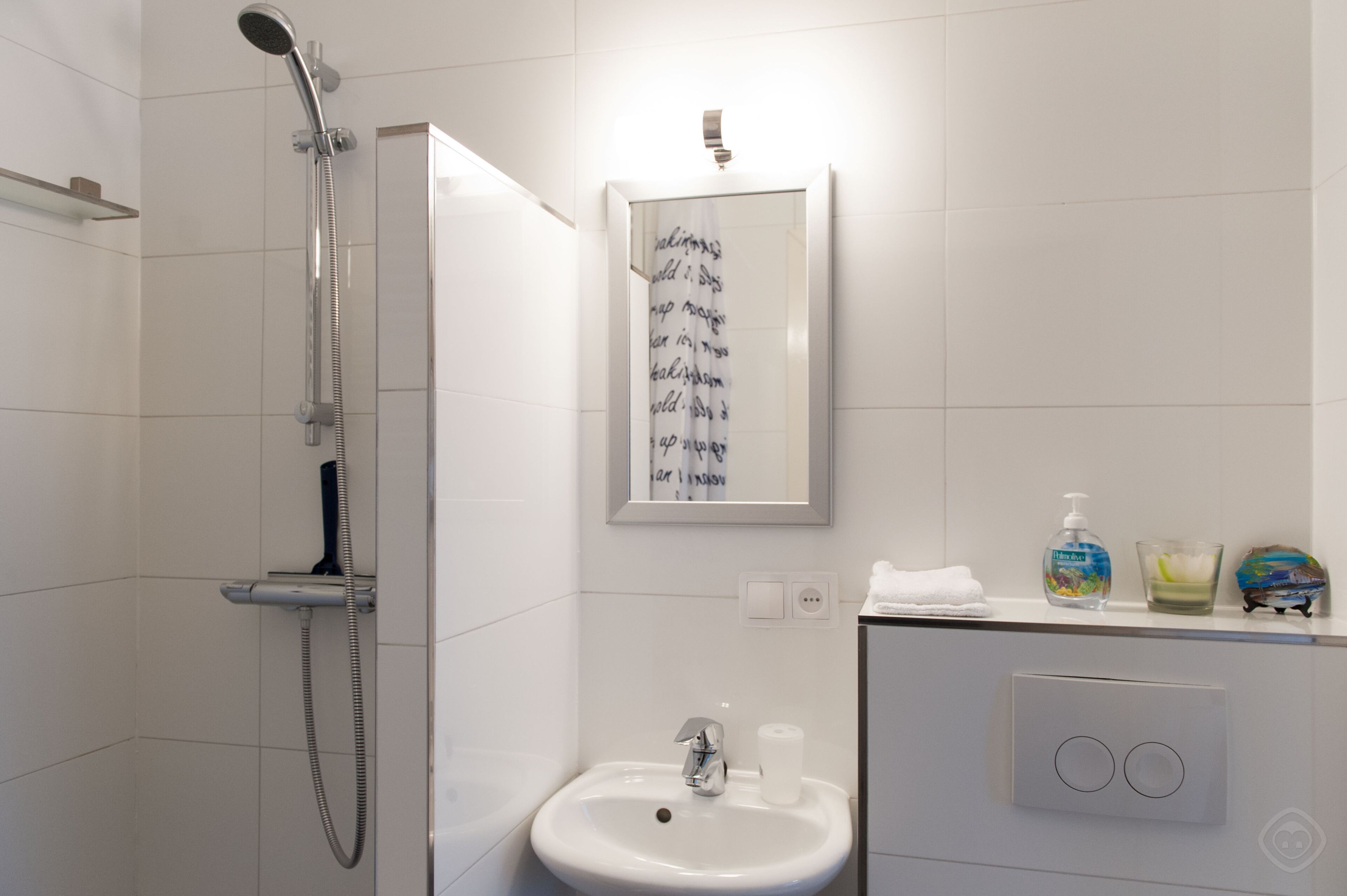 A modern bathroom with a shower, sink, and a framed artwork on the wall.