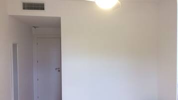 Una habitación con cama, una puerta y un ventilador de techo.