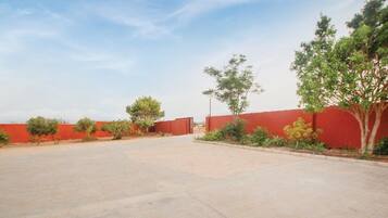 A paved courtyard with red walls and trees.