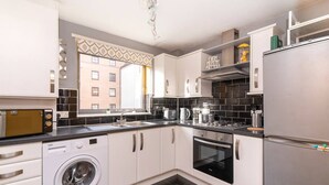 A compact kitchen with a washing machine, oven, and a microwave.