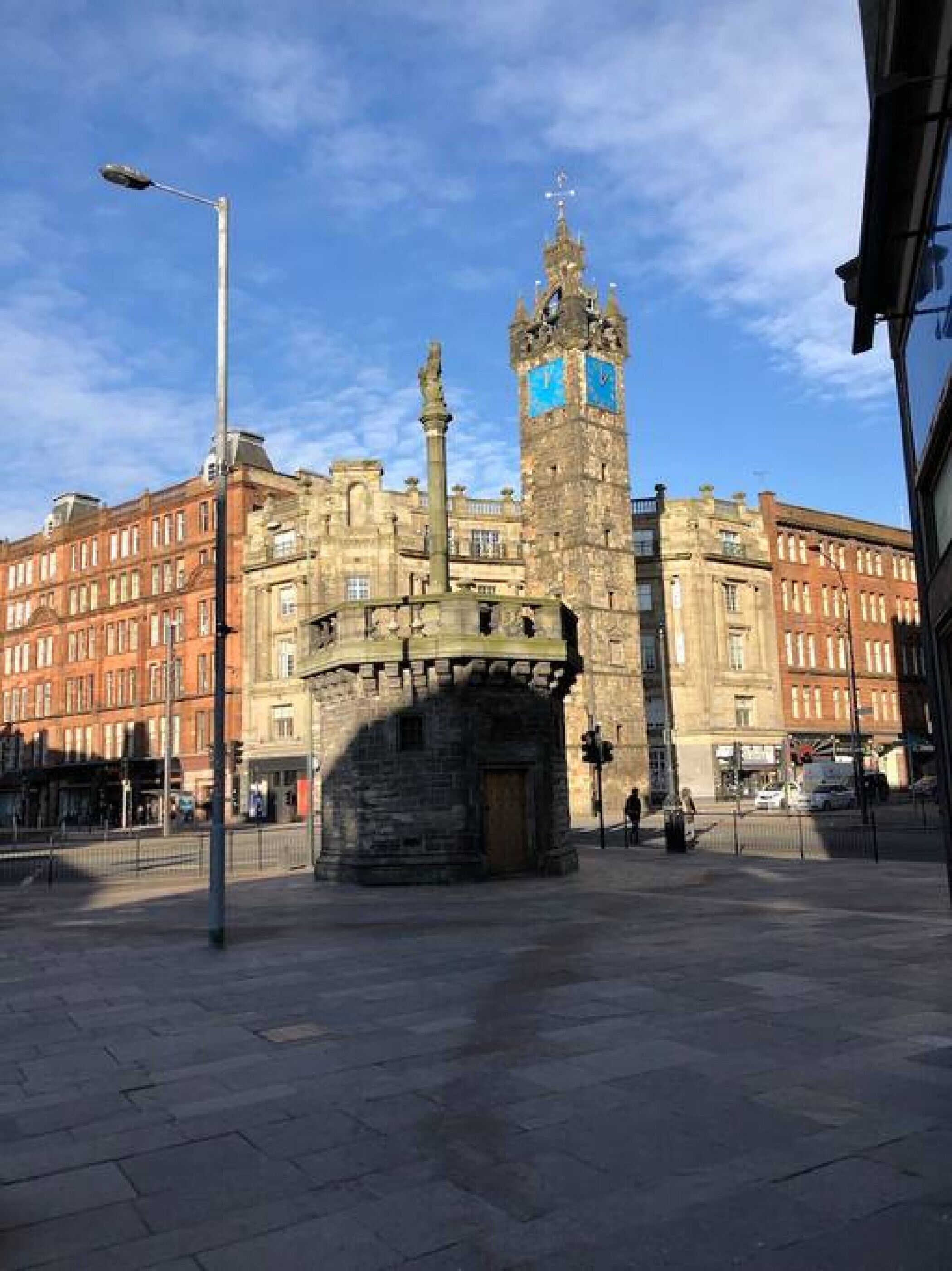 A historic square with a prominent clock tower and a central monument.