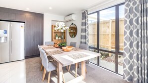 A modern kitchen with a built-in refrigerator, wooden cabinets, and a dining area with a table set for four. - Restful in Riccarton - Christchurch (Christchurch)