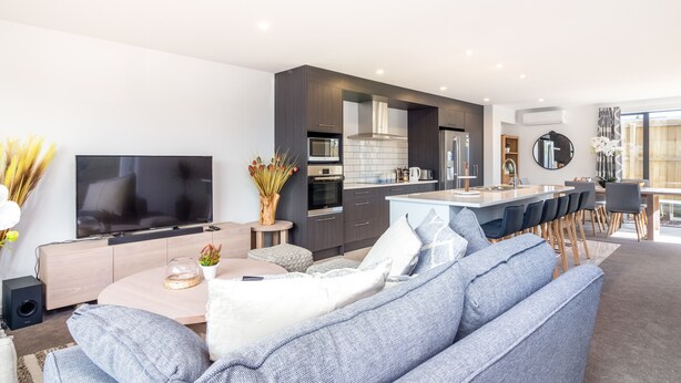 A modern living room with a large flat-screen TV, a sofa, and a coffee table. - Restful in Riccarton - Christchurch (Christchurch)