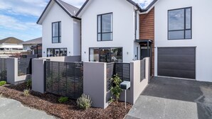 A modern two-story residential building with a flat roof, large windows, and a dark garage door. - Restful in Riccarton - Christchurch (Christchurch)