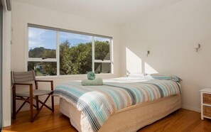 Enjoy a peaceful retreat with a view of lush greenery and rolling hills from the comfort of this serene bedroom.