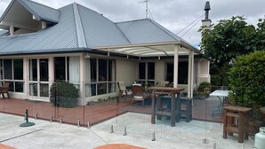 Una casa con porche cubierto, piscina y jardín.